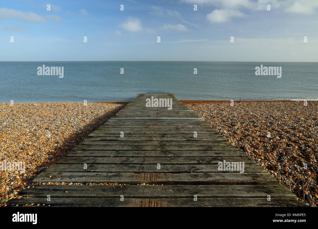 A wooden slipway leads from the shingle beach to the sea at Sandwich Bay, Kent, UK. Stock Photo