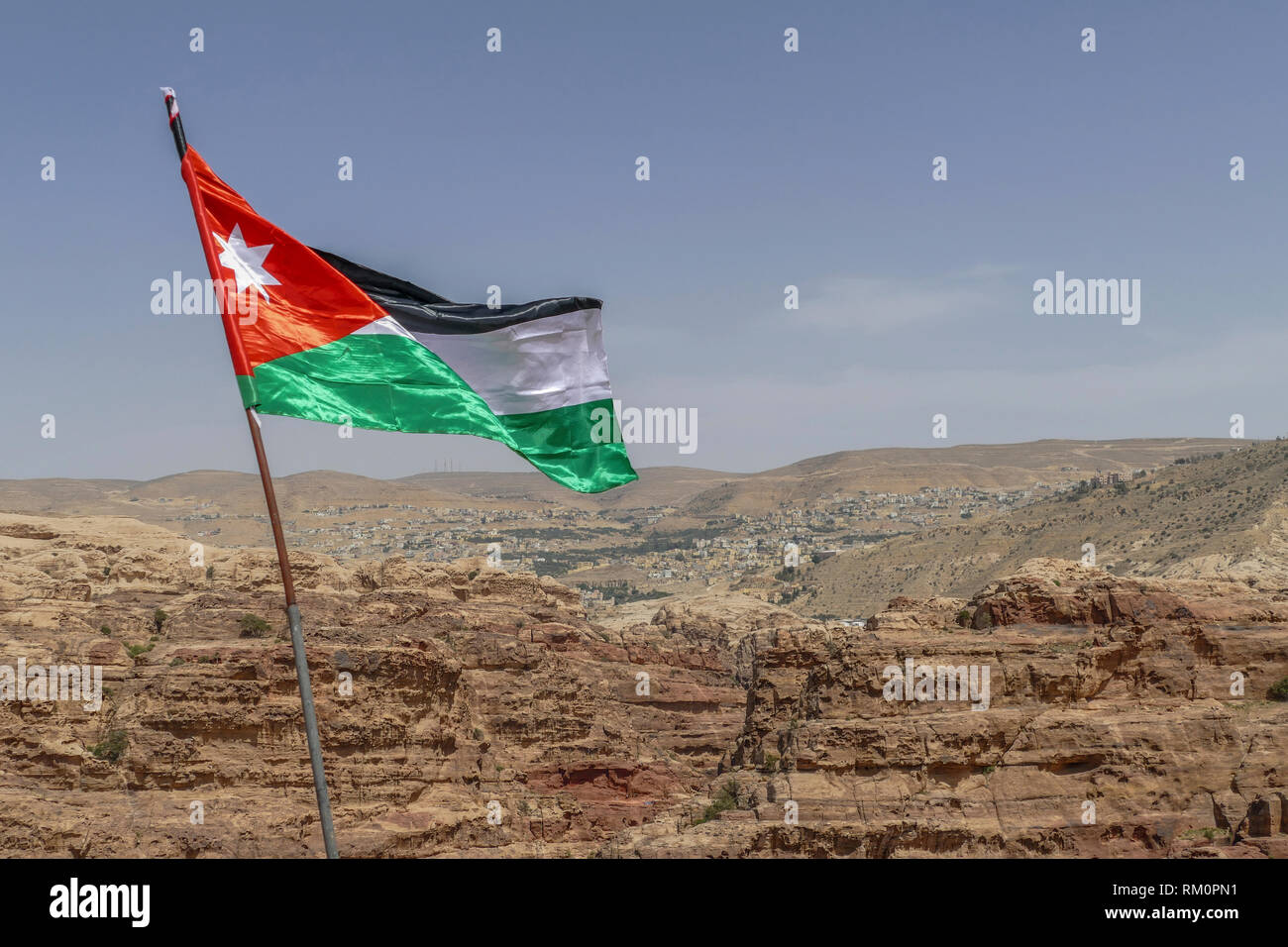 The Jordanian flag ripples in the wind over Petra in Jordan. Stock Photo