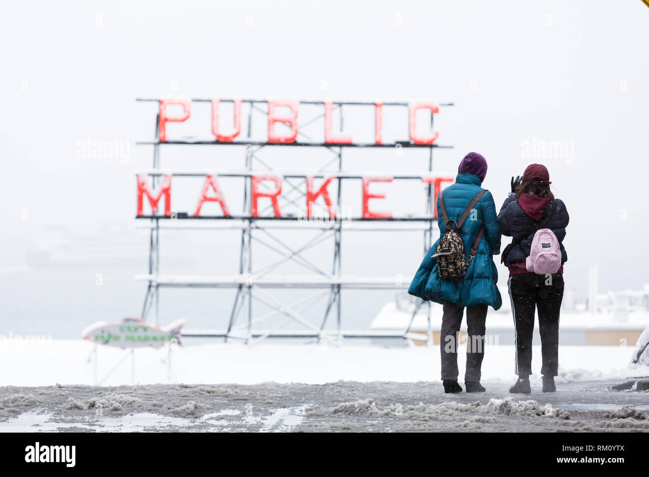 Seattle, Washington: Visitors stop to take a photo  of Pikes Place Market as a strong winter storm blankets Seattle in six inches of snow. Stock Photo