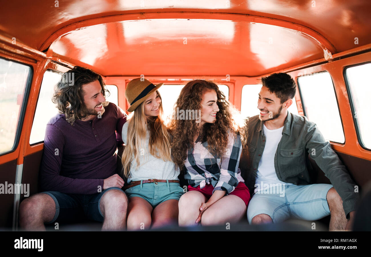 A group of young friends on a roadtrip through countryside, sitting in a minivan. Stock Photo