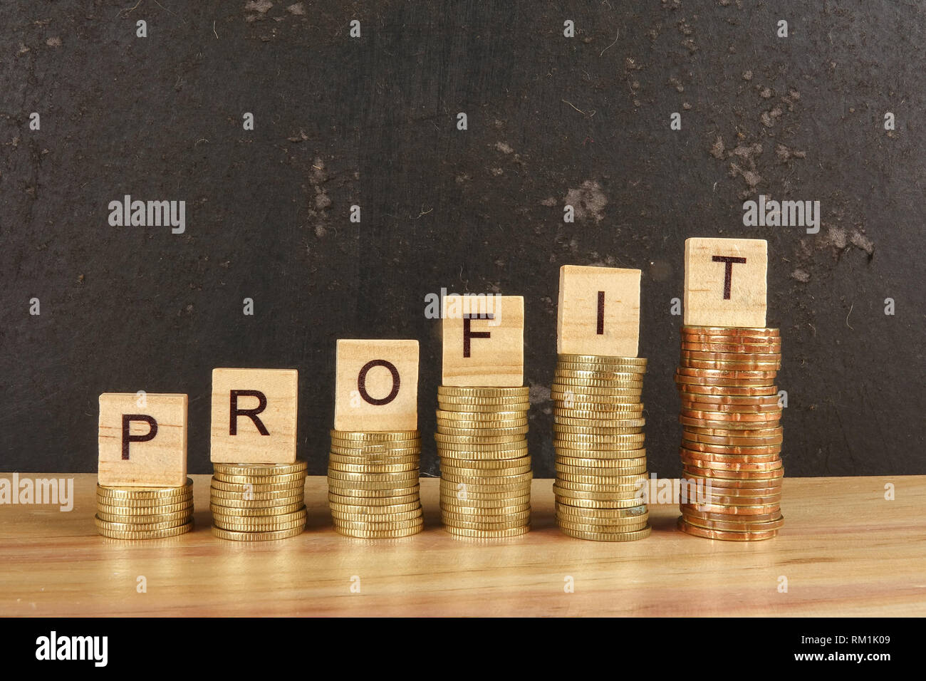 Business concept with PROFIT word on wooden plate onto hike trend stacked of coins. Stock Photo