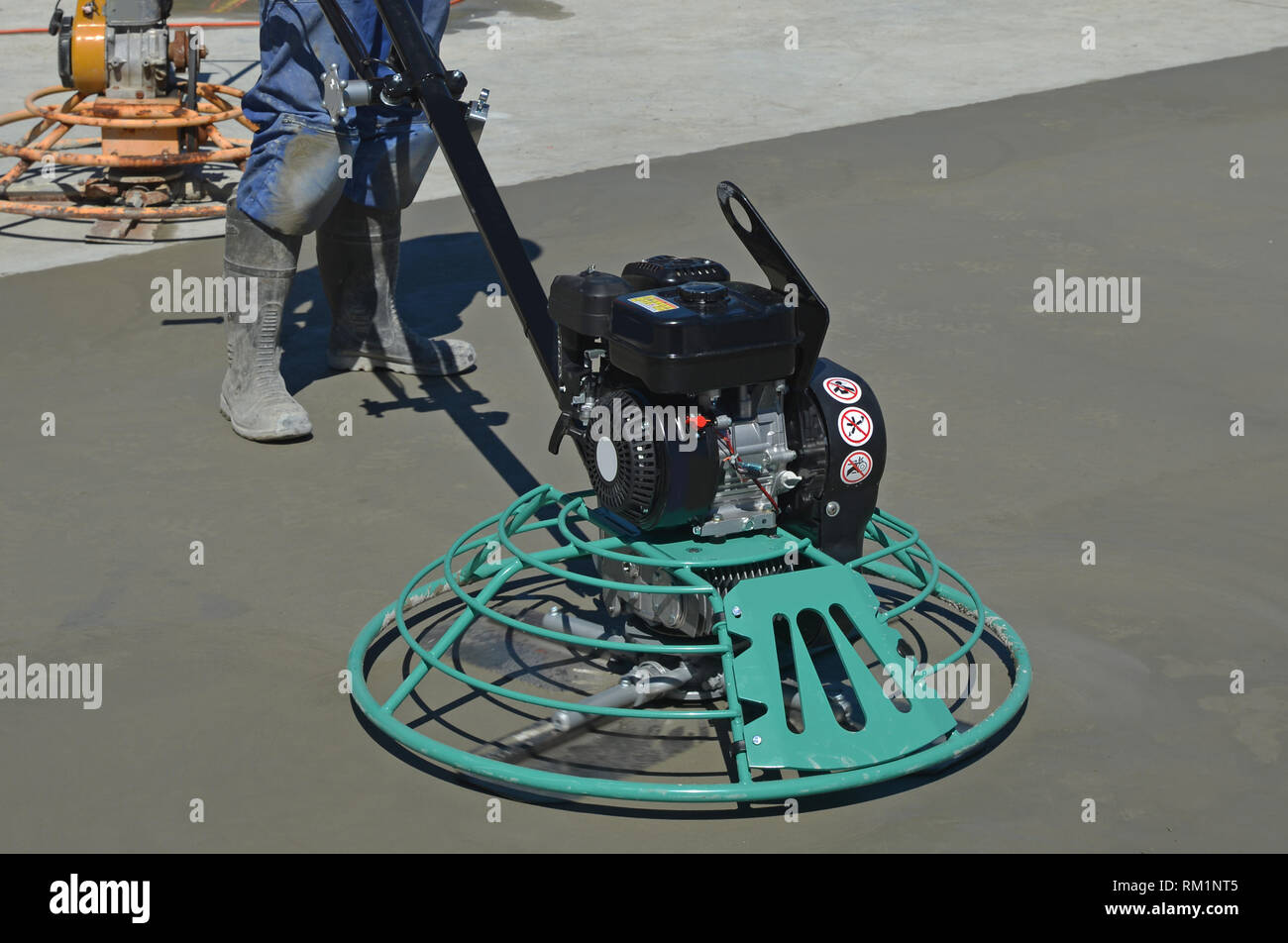 A builder uses a mechanical float to smooth new concrete for a large