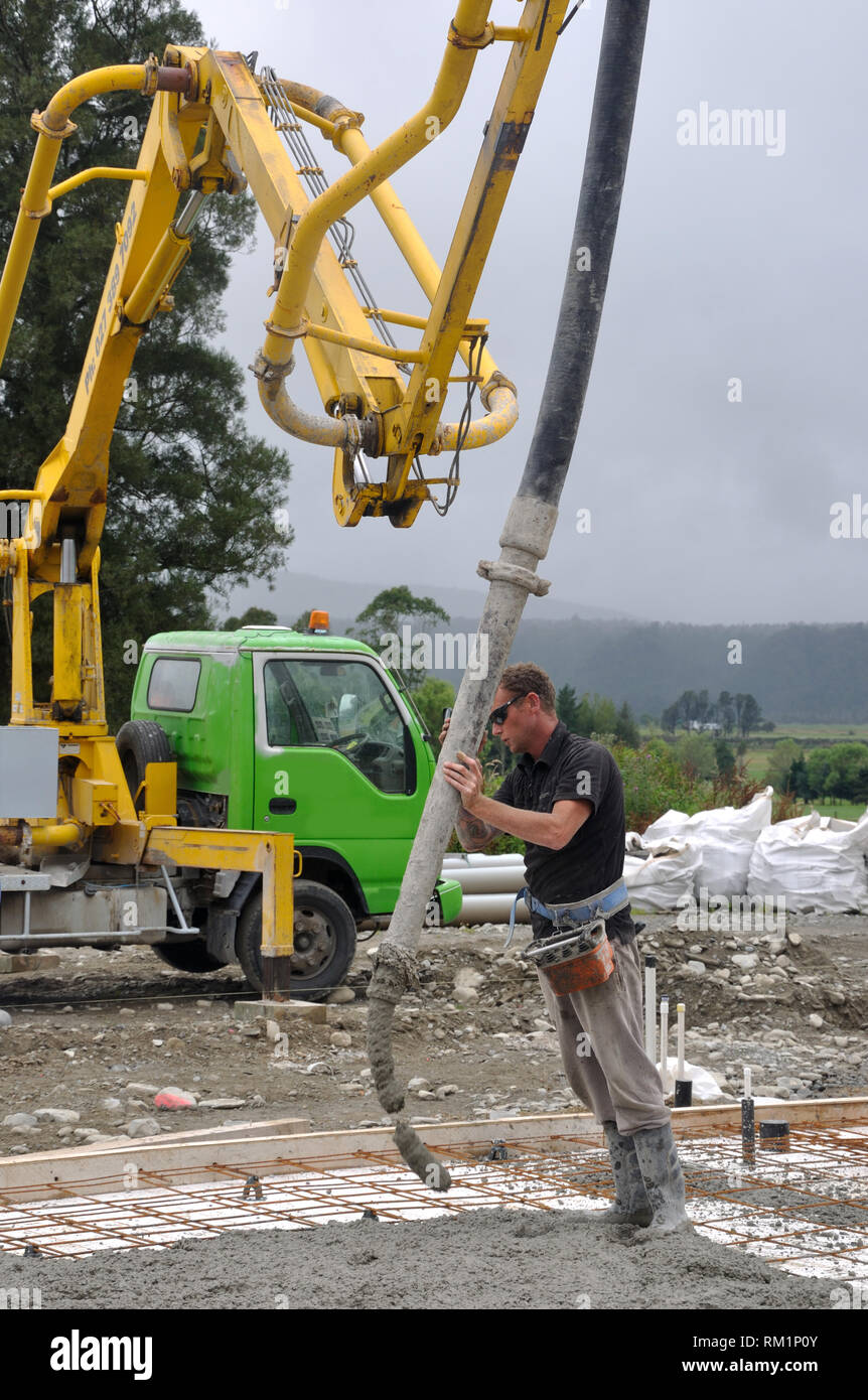 Builder uses a concrete pump to direct wet concrete into the foundations of a large building Stock Photo