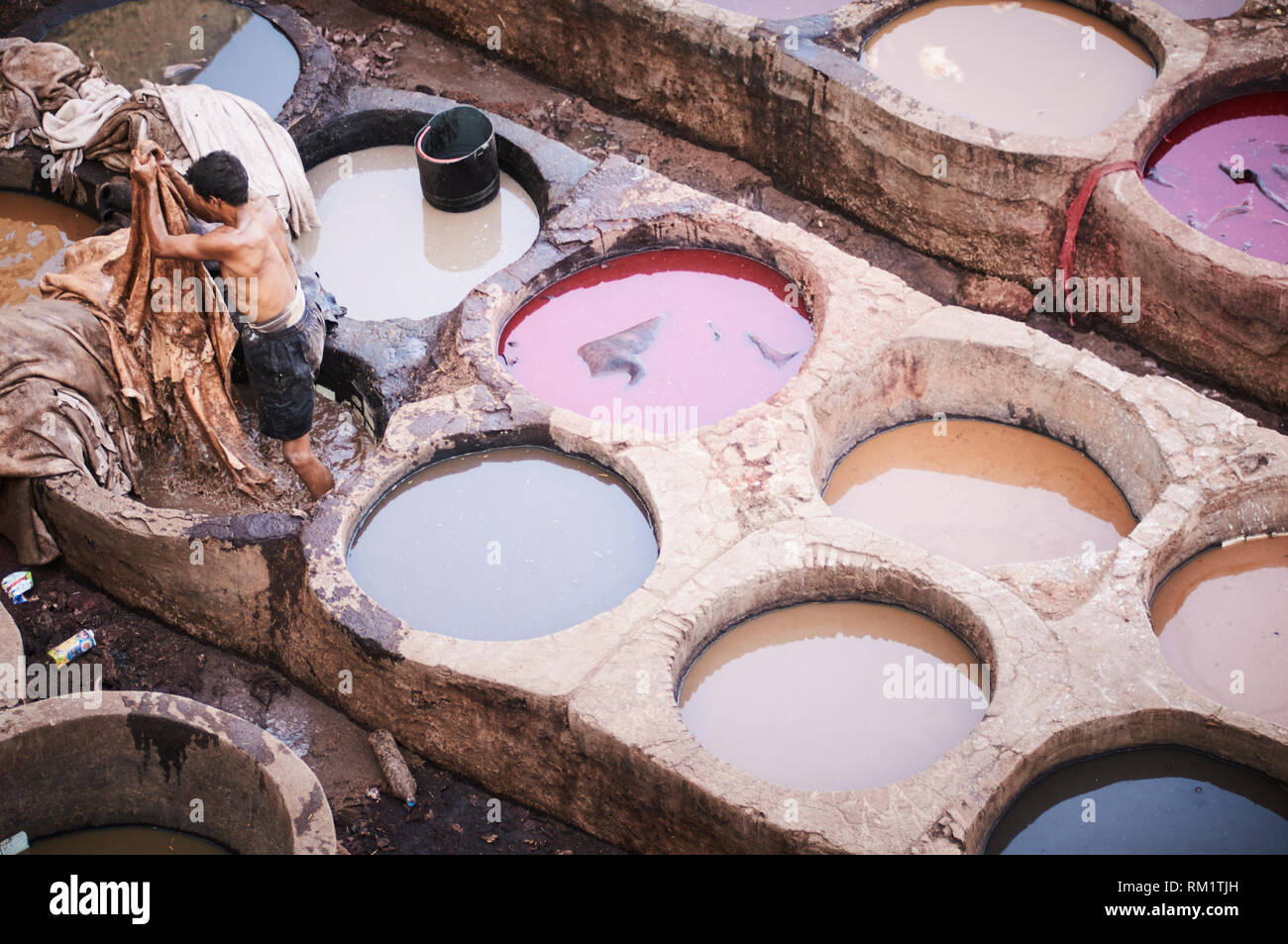 Men in the Chouara Tannery dye and treat leather hides for the production of leather goods, in the Fes al Bali medina in Fes, Morocco. Stock Photo