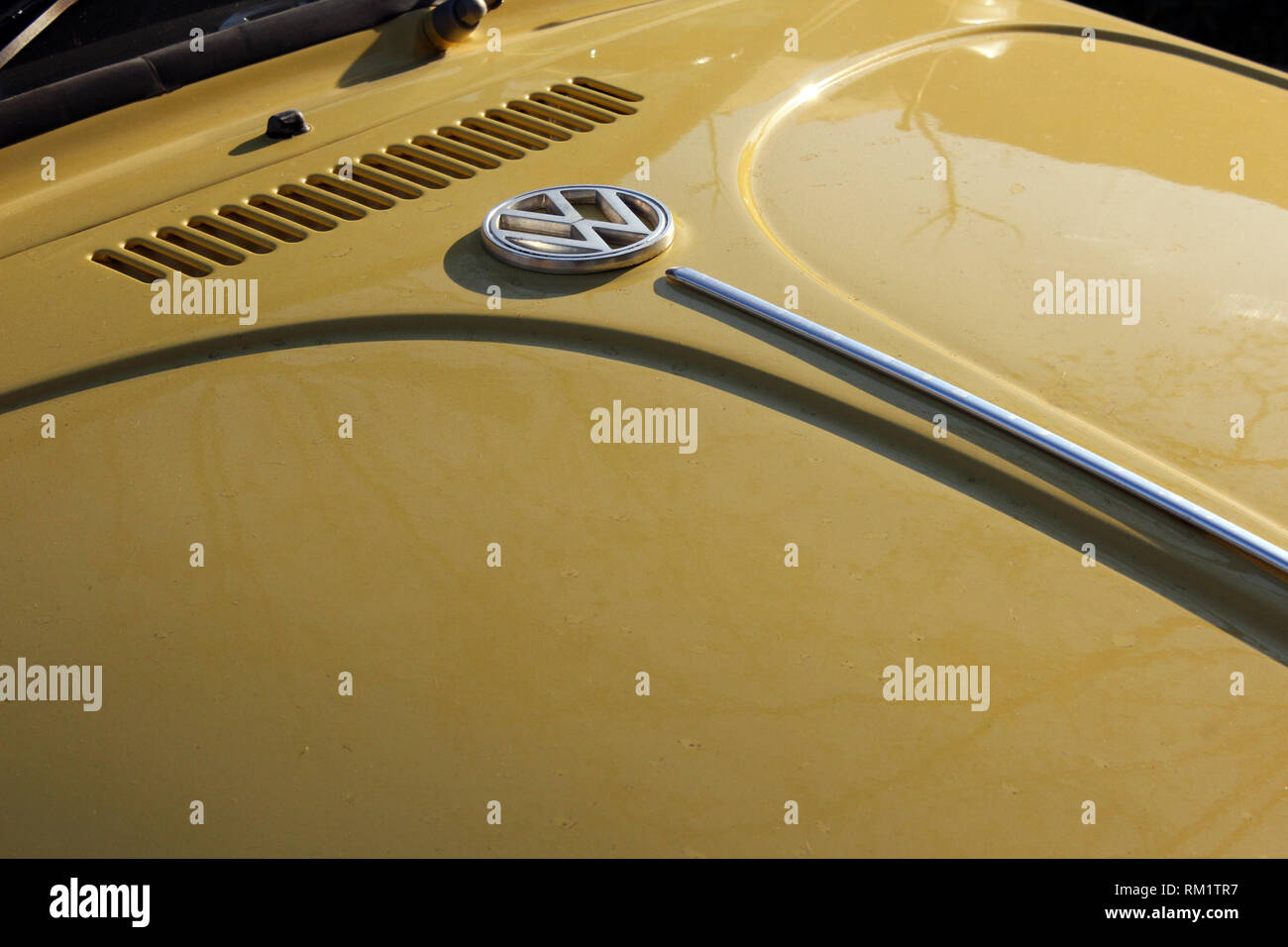 Old yellow Volkswagen beetle hood with brand logo badge, close-up Stock Photo