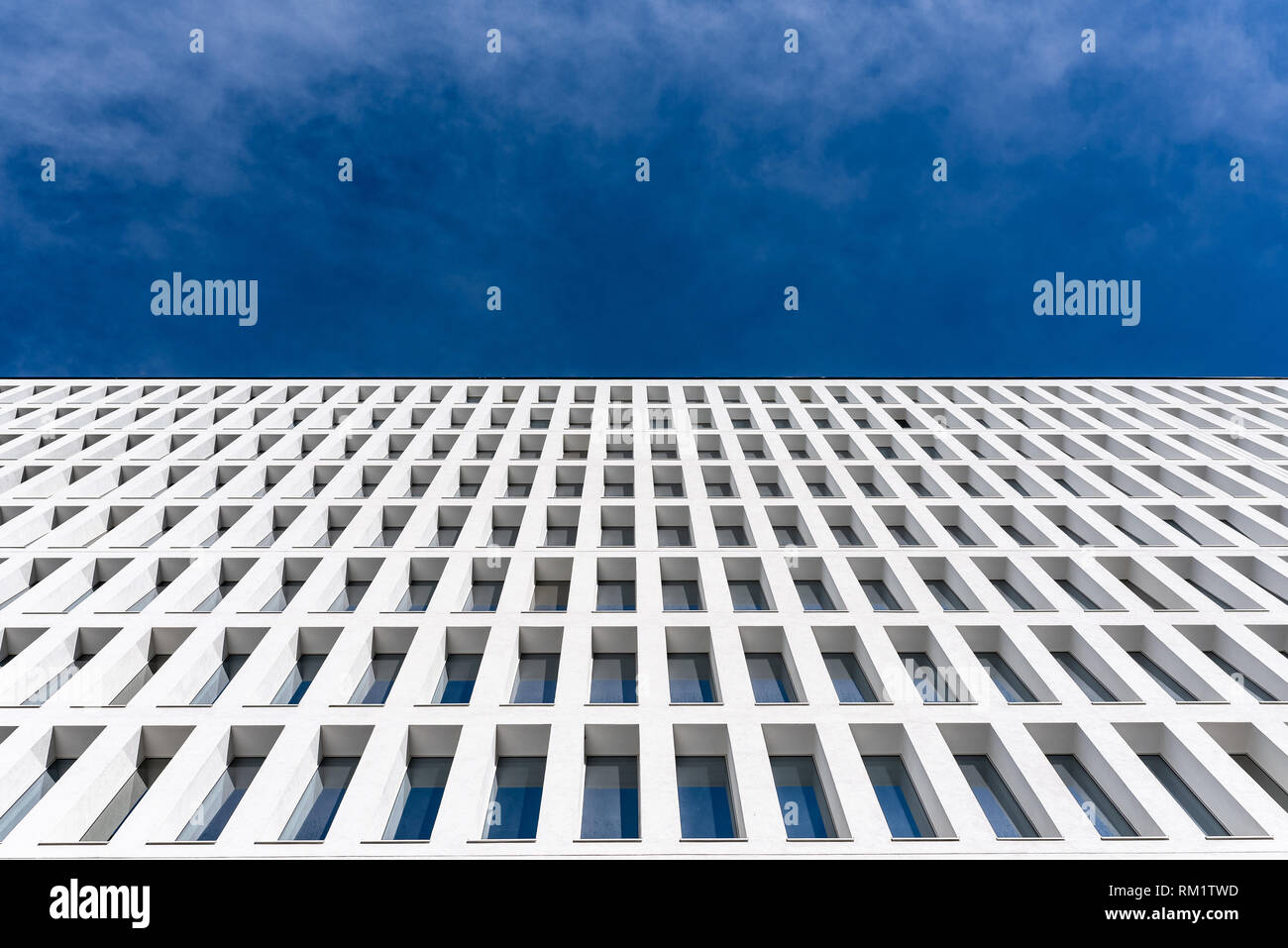 modern tertiary and businness building with white facade and windows that reflect the blue sky, different copyspace Stock Photo