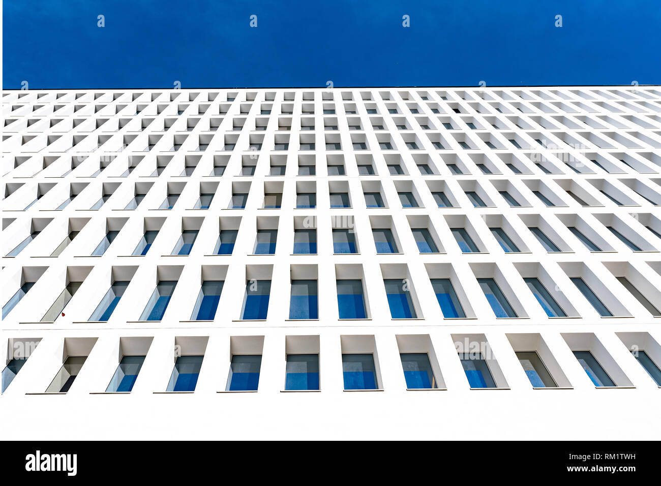 modern tertiary and businness building with white facade and windows that reflect the blue sky, pattern Stock Photo