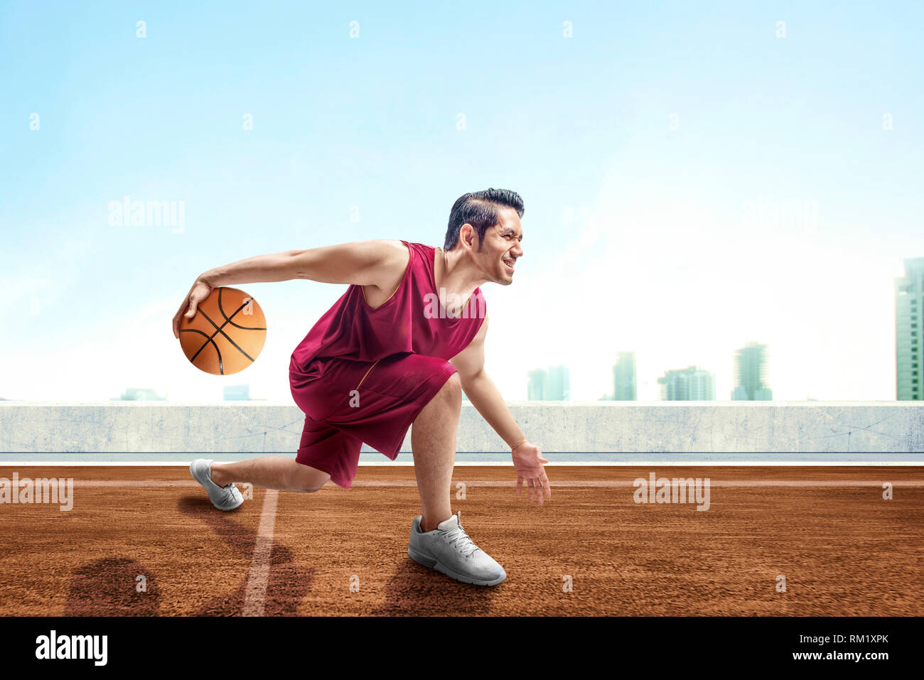 Young asian man basketball player posing in dribbling the ball between