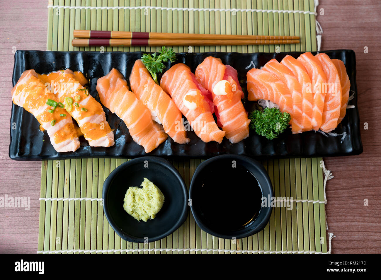 Mixed Salmon Sushi And Sashimi On Black Plate Along With Japanese
