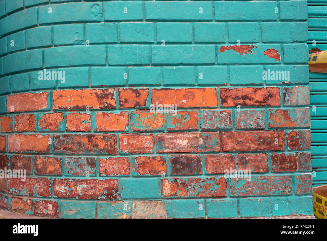 Colourful wall surface with exposed bricks texture and turquoise paint. Urban details for backdrop, wallpaper, RF. La Candelaria, Bogota, Colombia Stock Photo