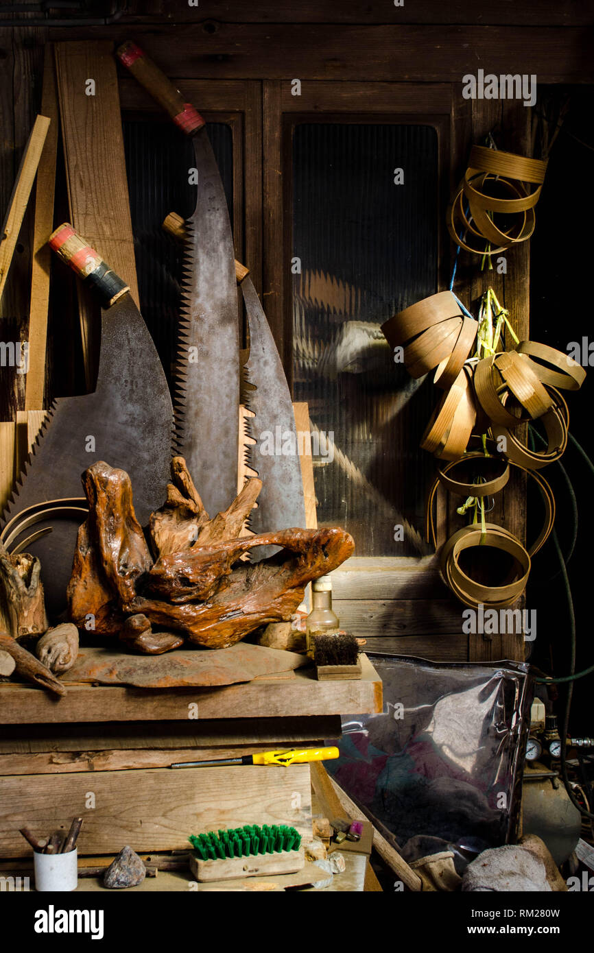 Large saws, burl wood, and miscellaneous woodworking equipment in front of an old shop in the village of Umaji, Kochi prefecture, Shikoku, Japan Stock Photo