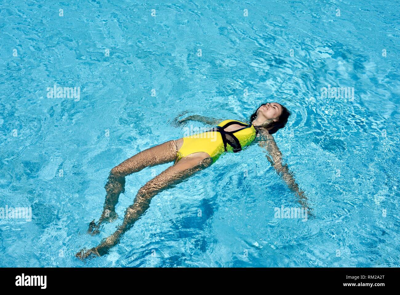woman floating, in pool, relaxation, recreation, summer, holiday Stock