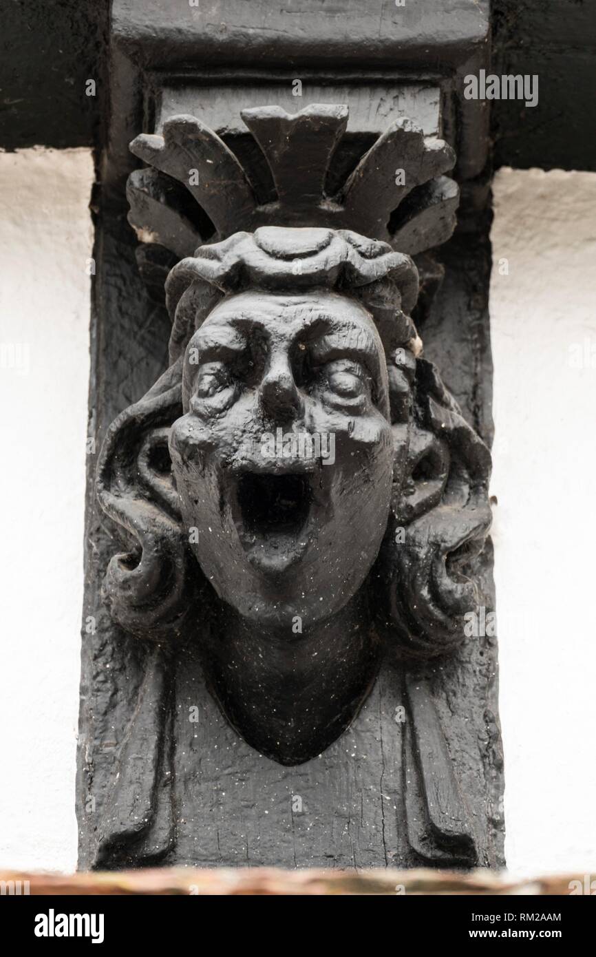 Comic black lacquered wooden finial of a laughing man with stylised crown on the old timber framed museum of Hereford, England. Stock Photo