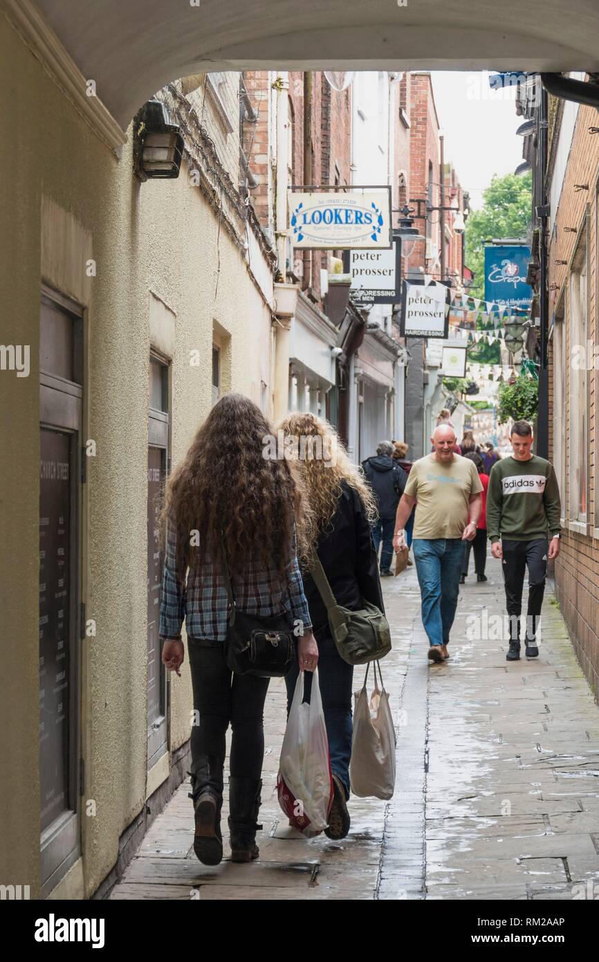 Girls with blonde and brown identical long curly hair walking through an arcade in Hereford's bunting filled artisan quarter, Hereford, England. Stock Photo