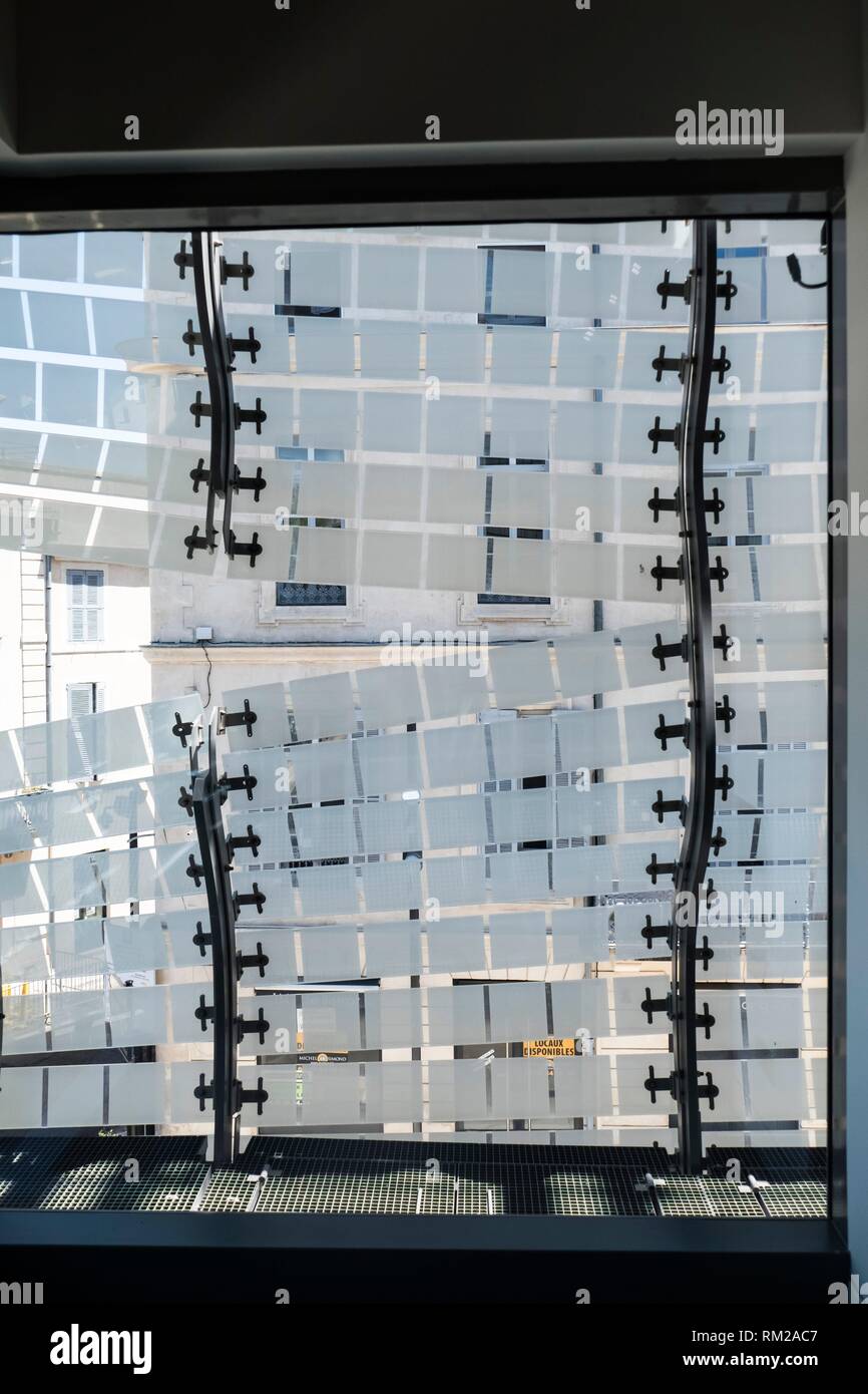 Mosaic of reflective square cladding, held by sinuus spinal column style metal rivets, revealing the repeating classical windows forms of the facing Stock Photo