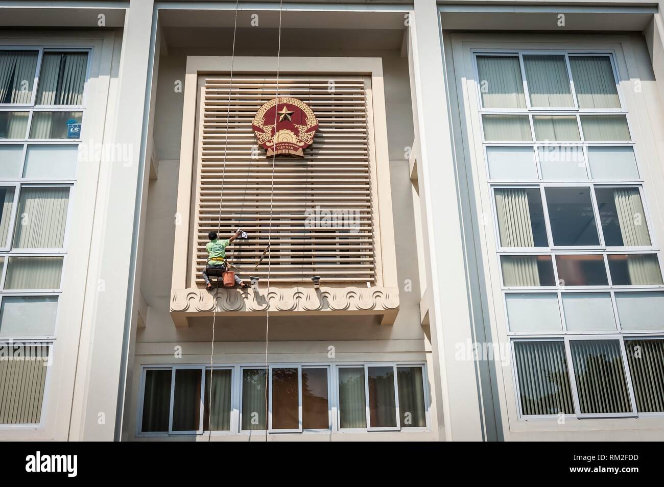 Worker cleaning the facade of governmental building in Hanoi, Vietnam. Stock Photo