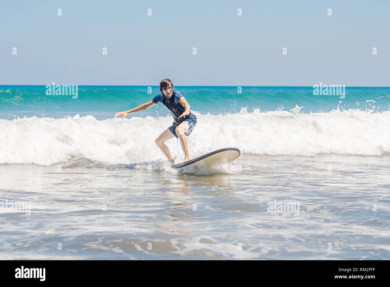 Young Man Beginner Surfer Learns To Surf On A Sea Foam On Young Man Beginner Surfer Learns To Surf On A Sea Foam On