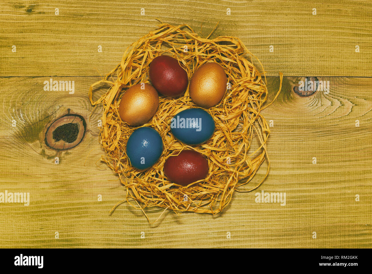 Painted Easter eggs in a straw on wooden table.Toned photo Stock Photo ...