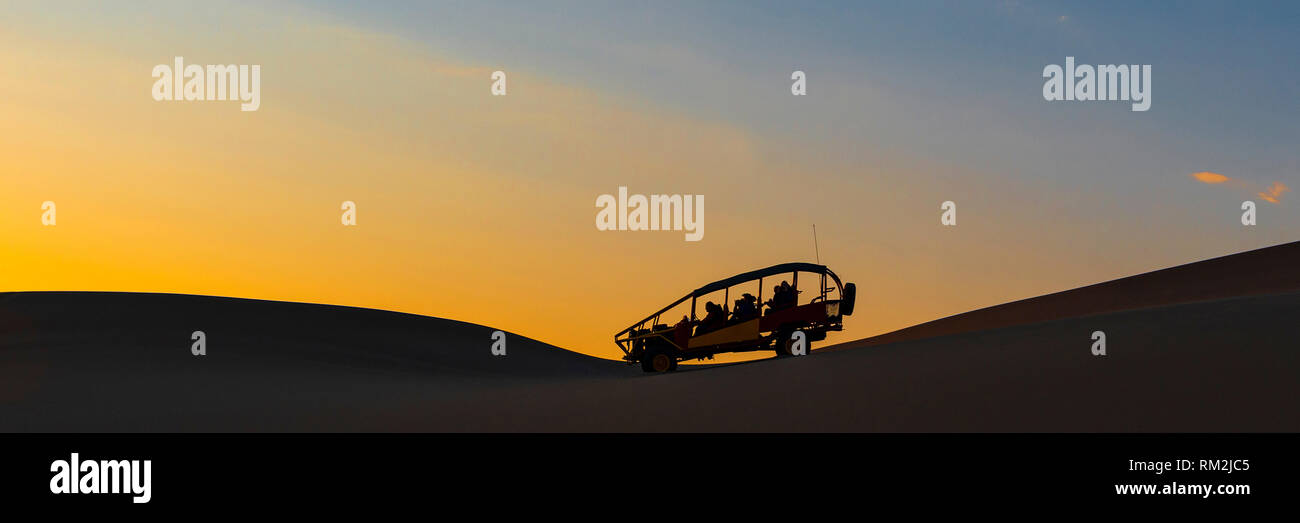 Panorama with the silhouette of a buggy at sunset in the coastal Peruvian desert between Ica and Huacachina, Peru. Stock Photo