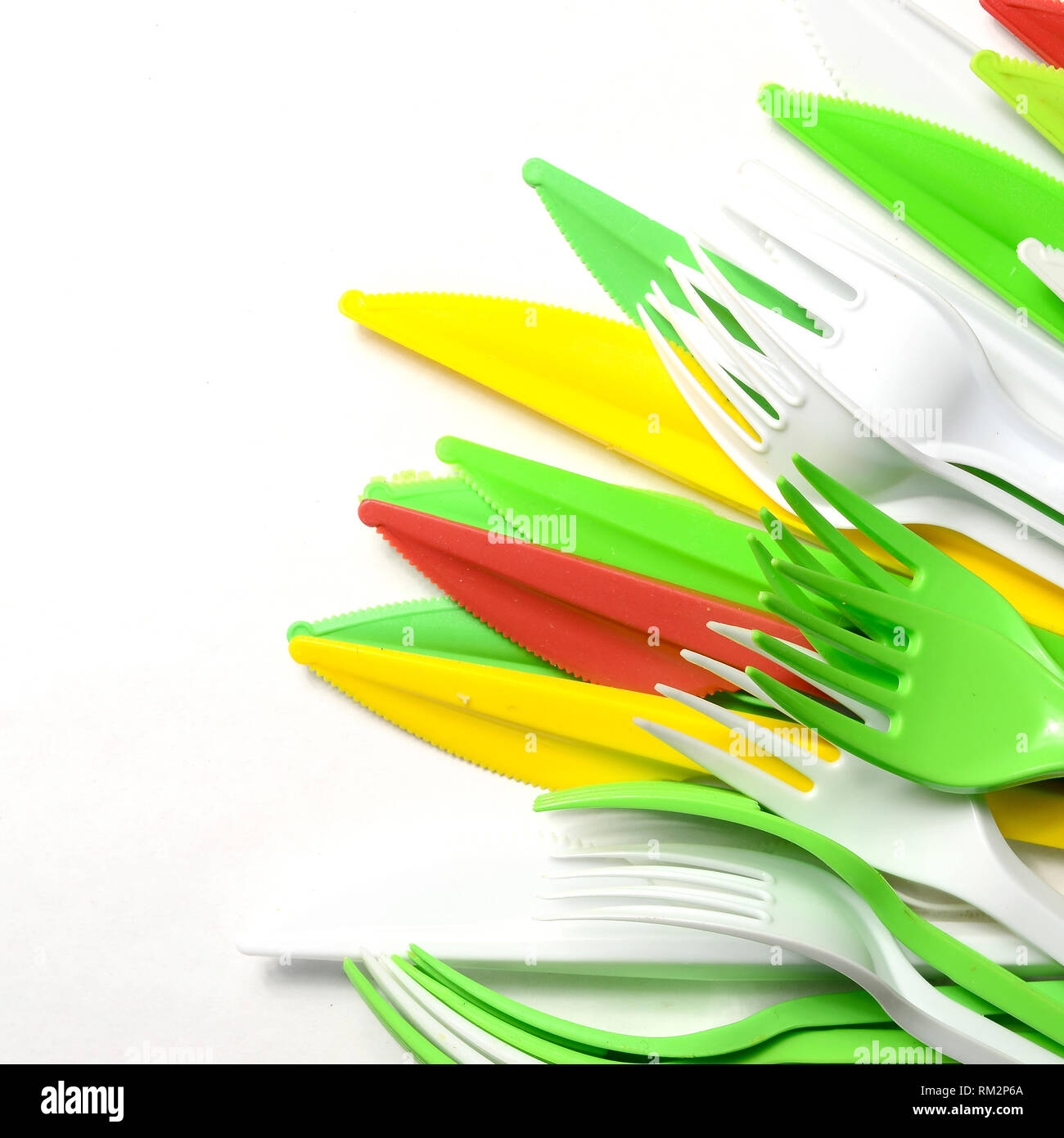 Pile of bright yellow, green and white plastic kitchenware single use appliances on white background Stock Photo