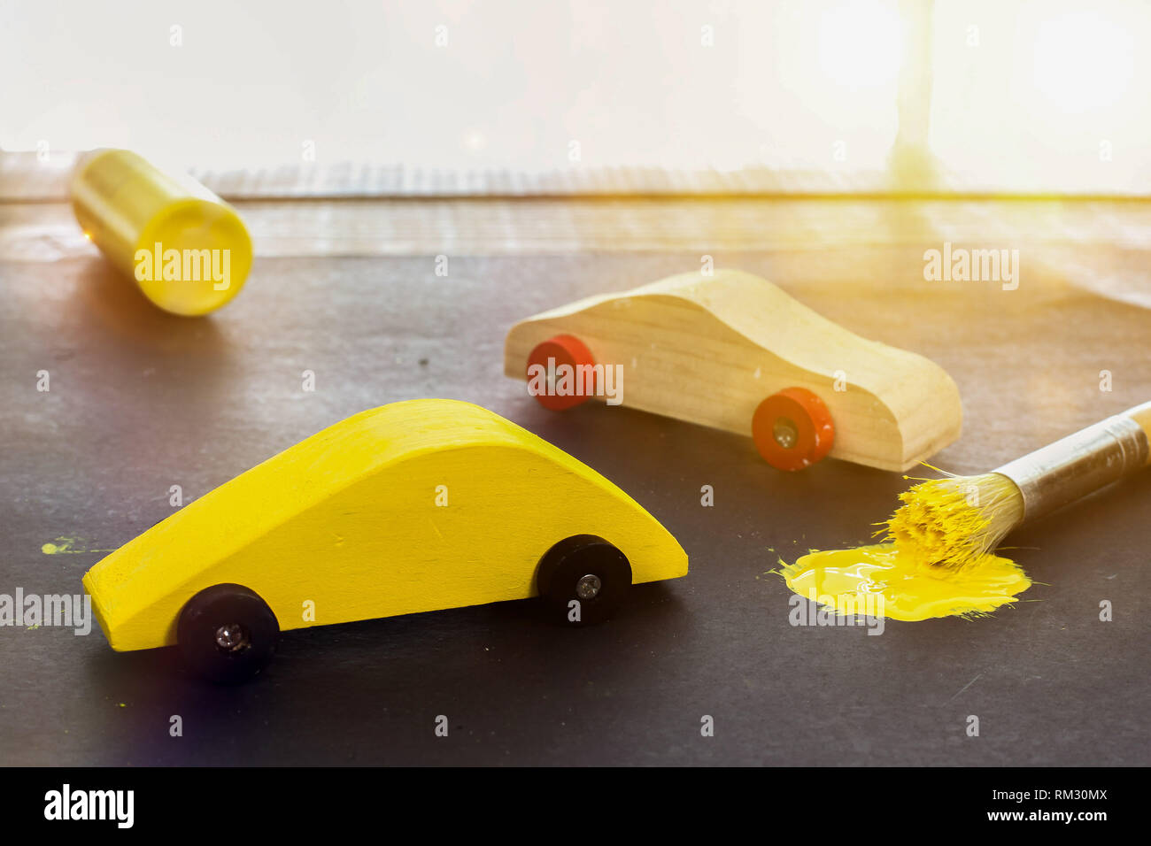 Toy cars with yellow paint brush and sunbeam from window Stock Photo