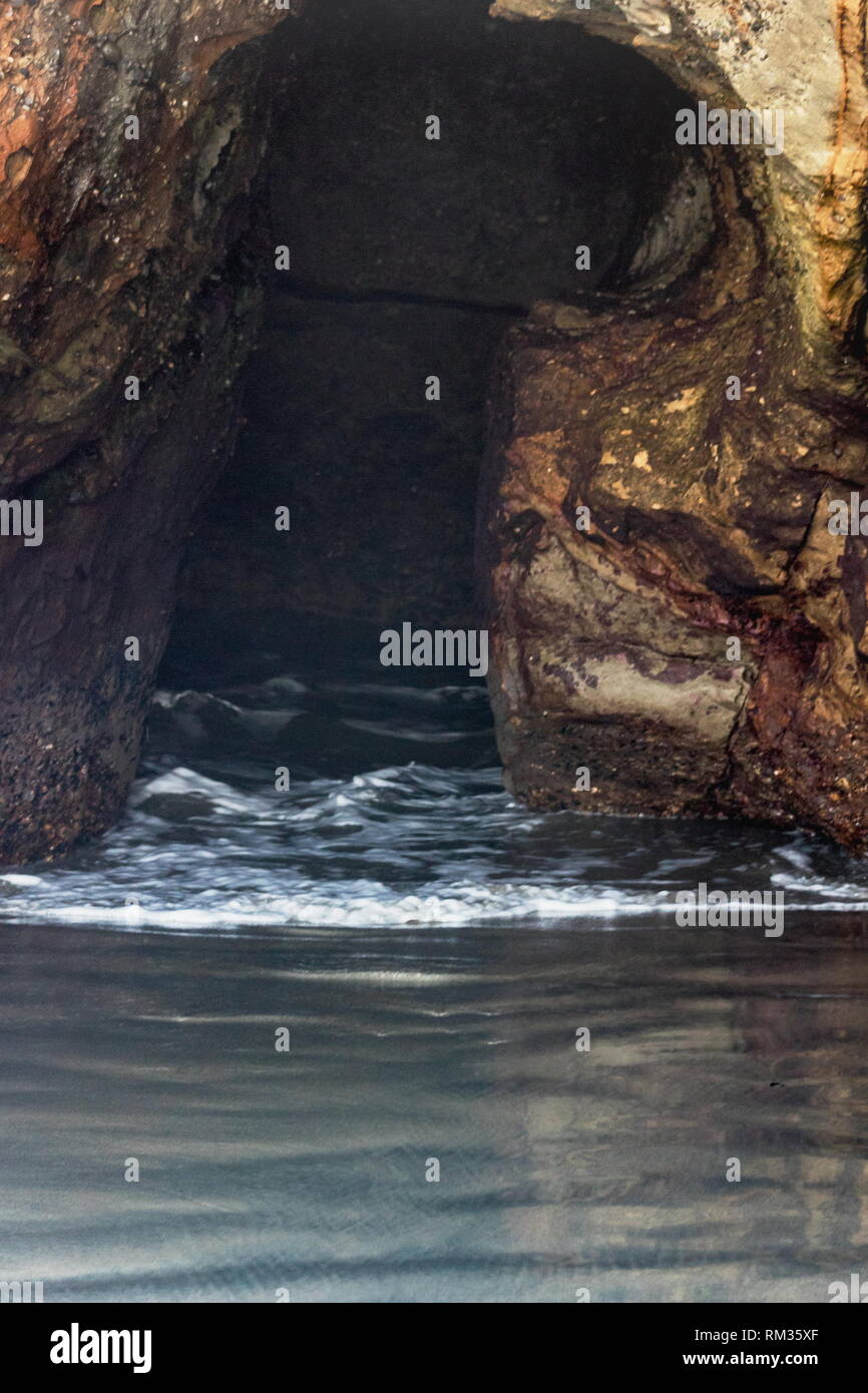 Natural formed cave where the ocean comes through the rock at Wharariki