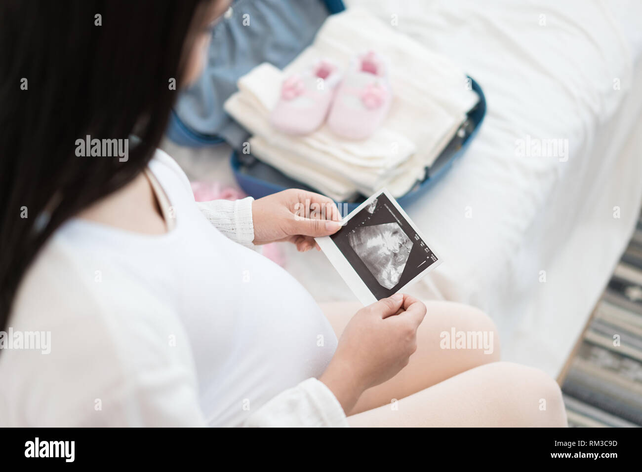 Pregnant woman holding ultrasound image. Concept of pregnancy, health care, gynecology, medicine. Young mother waiting of the baby. Close-up, copy spa Stock Photo
