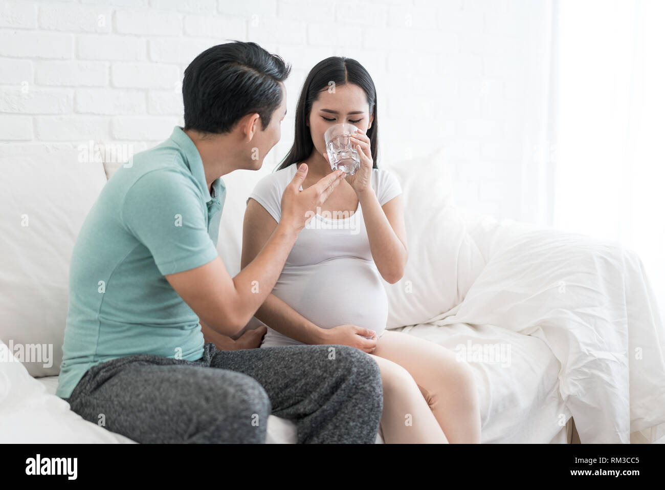 Pregnancy couple healthcare concept. Asian Pregnant woman drinks glass