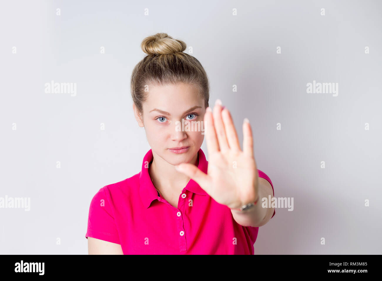 Portrait of a serious young womanin in pink dress standing with ...