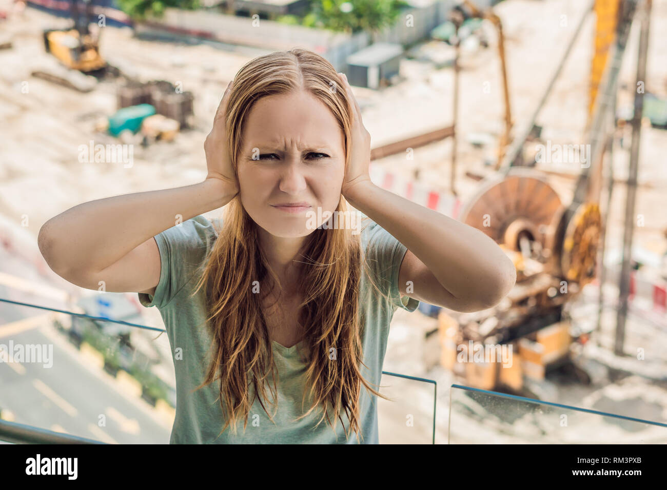 A young woman by the window annoyed by the building works outside ...