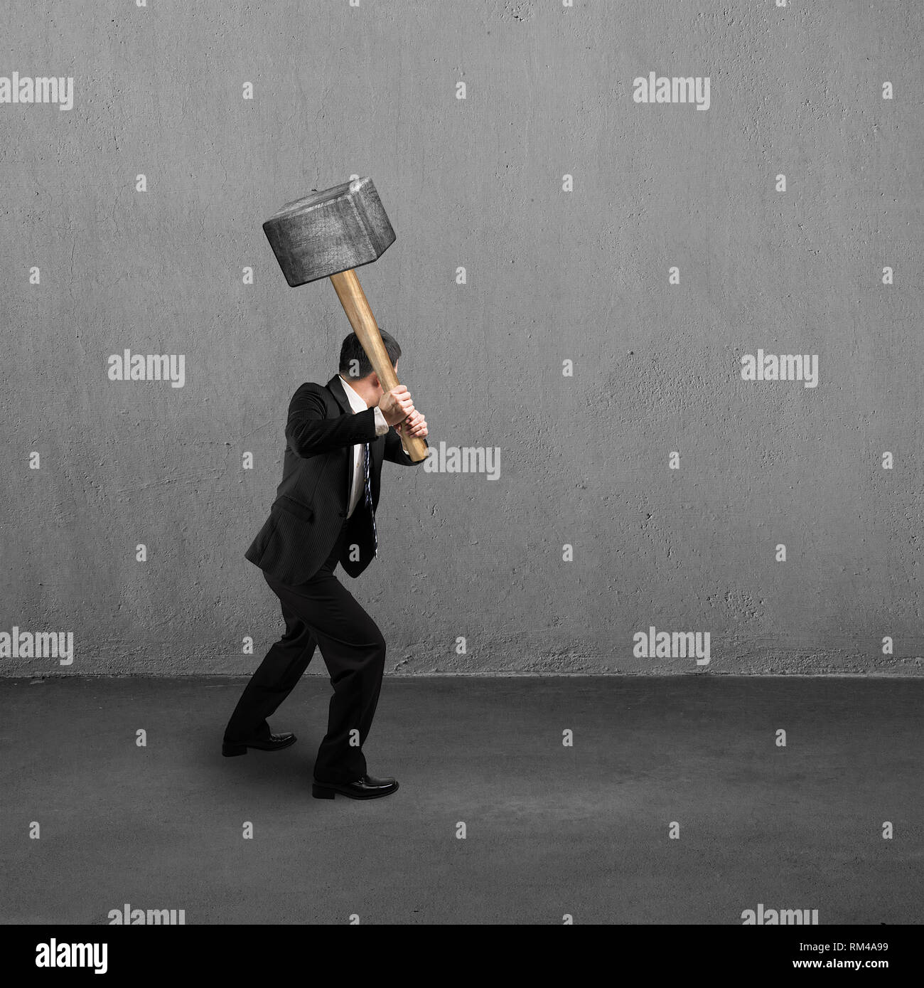Businessman using big hammer to creak concrete wall Stock Photo