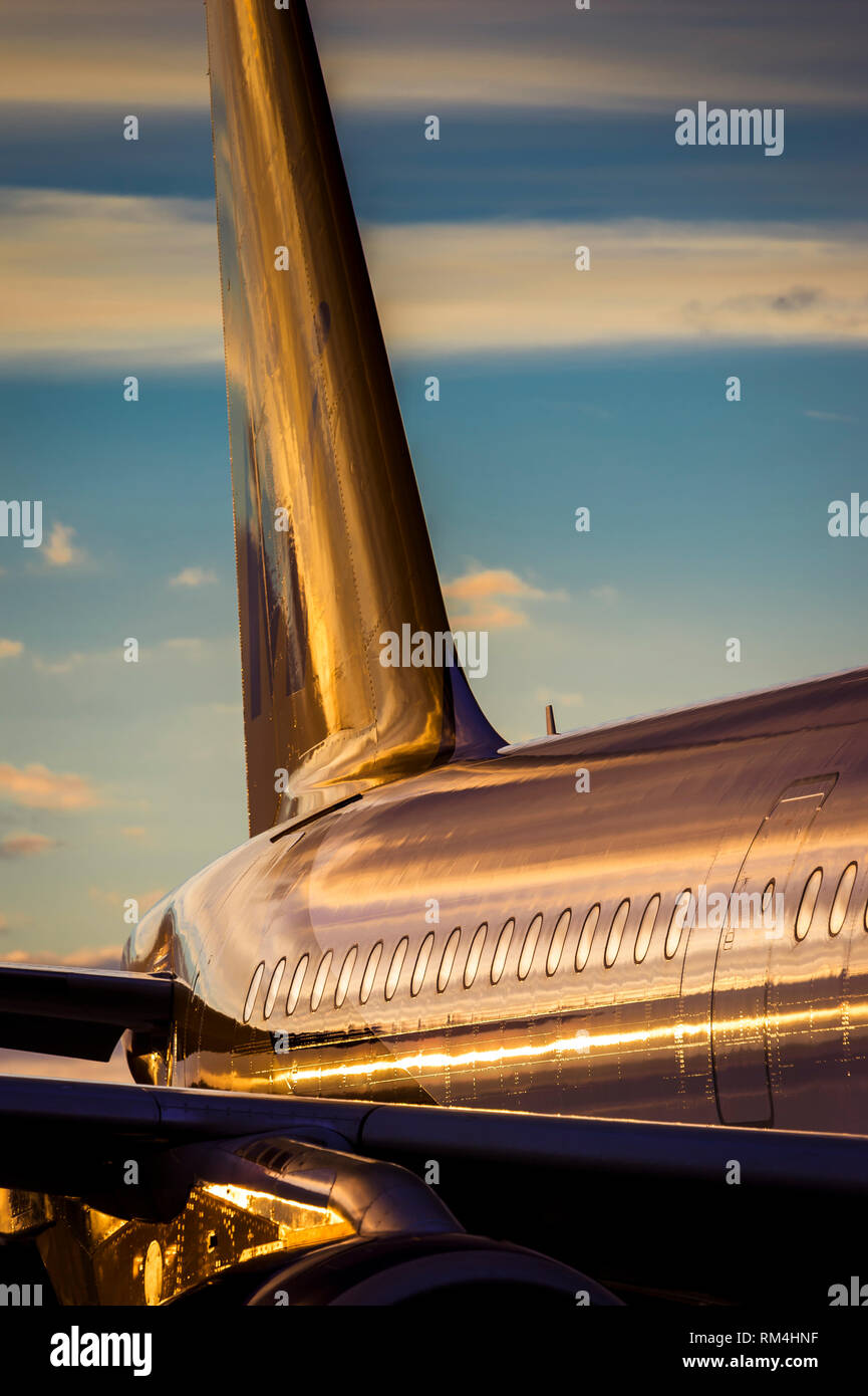 Close up of the tail assembly of an aircraft waiting on the apron at Gatwick Airport at dusk. Stock Photo