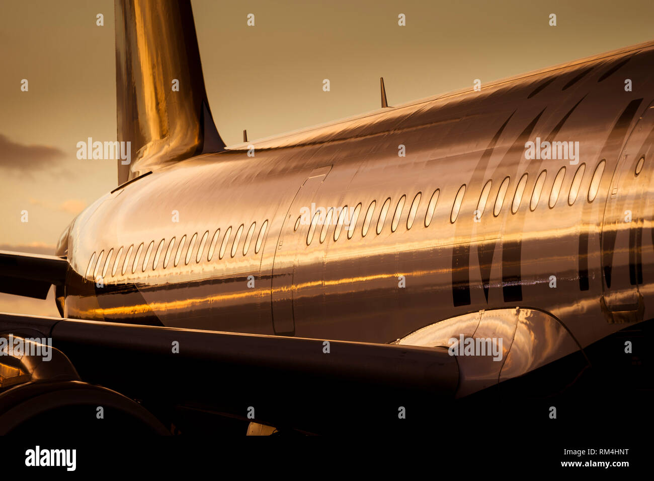 Close up of the tail and emergency exit door of an aircraft waiting on the apron at Gatwick Airport at dusk. Stock Photo