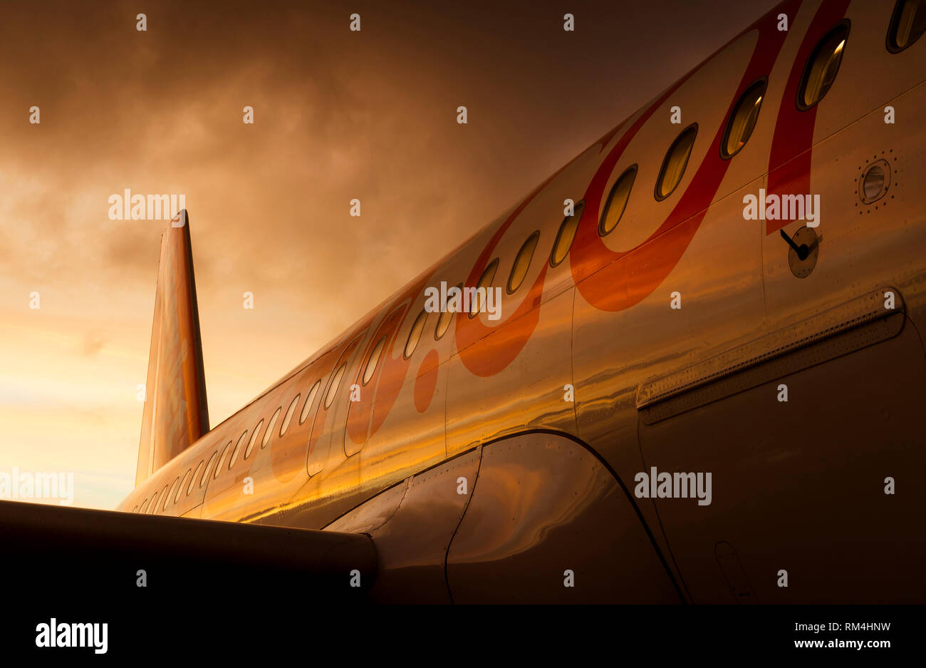 Close up of the tail and emergency exit door of an Easyjet aircraft waiting on the apron at Gatwick Airport at dusk. Stock Photo