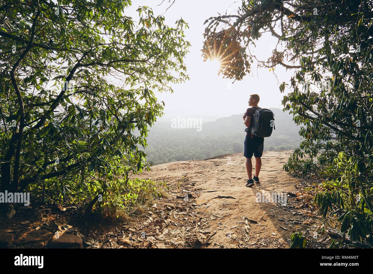 Young hiker overlooking view from rock. Landscape of Sri Lanka at sunset. Stock Photo