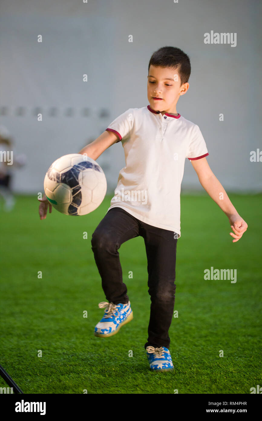 A little boy wearing white shirt throws the ball on the field and