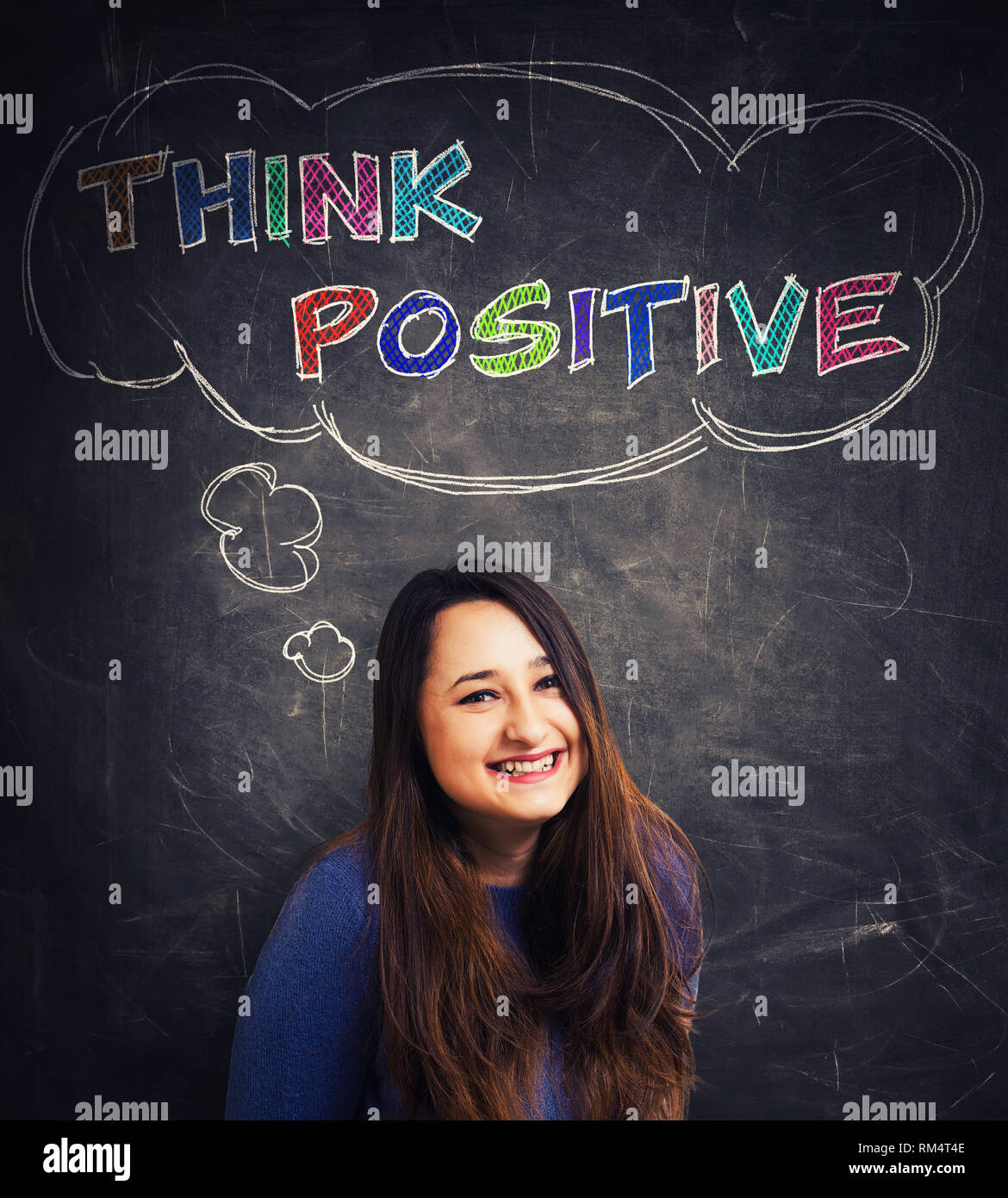 Cute young woman natural smile looking to camera isolated over blackboard background and a thought bubble with the text think positive. Colorful motiv Stock Photo