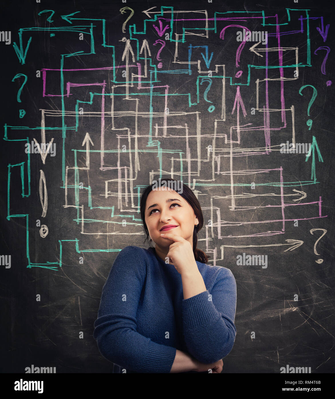 Puzzled young woman in front of blackboard with different colorful