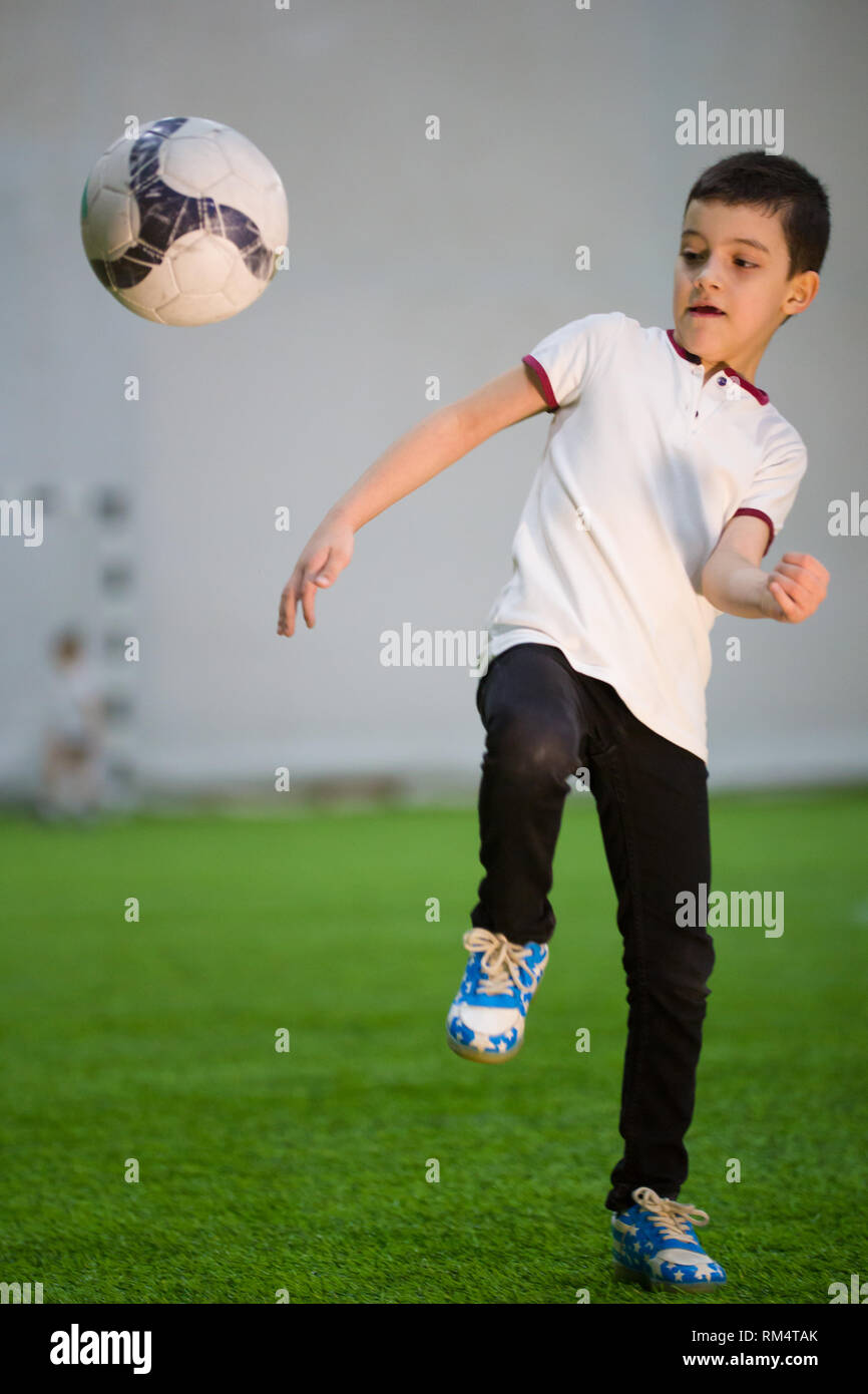 A little boy throwing the ball on the field playing football with other