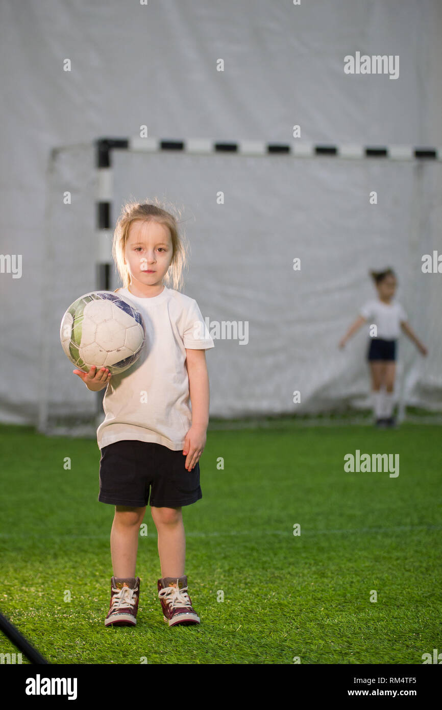 A little girl holding the ball in one hand on the football field