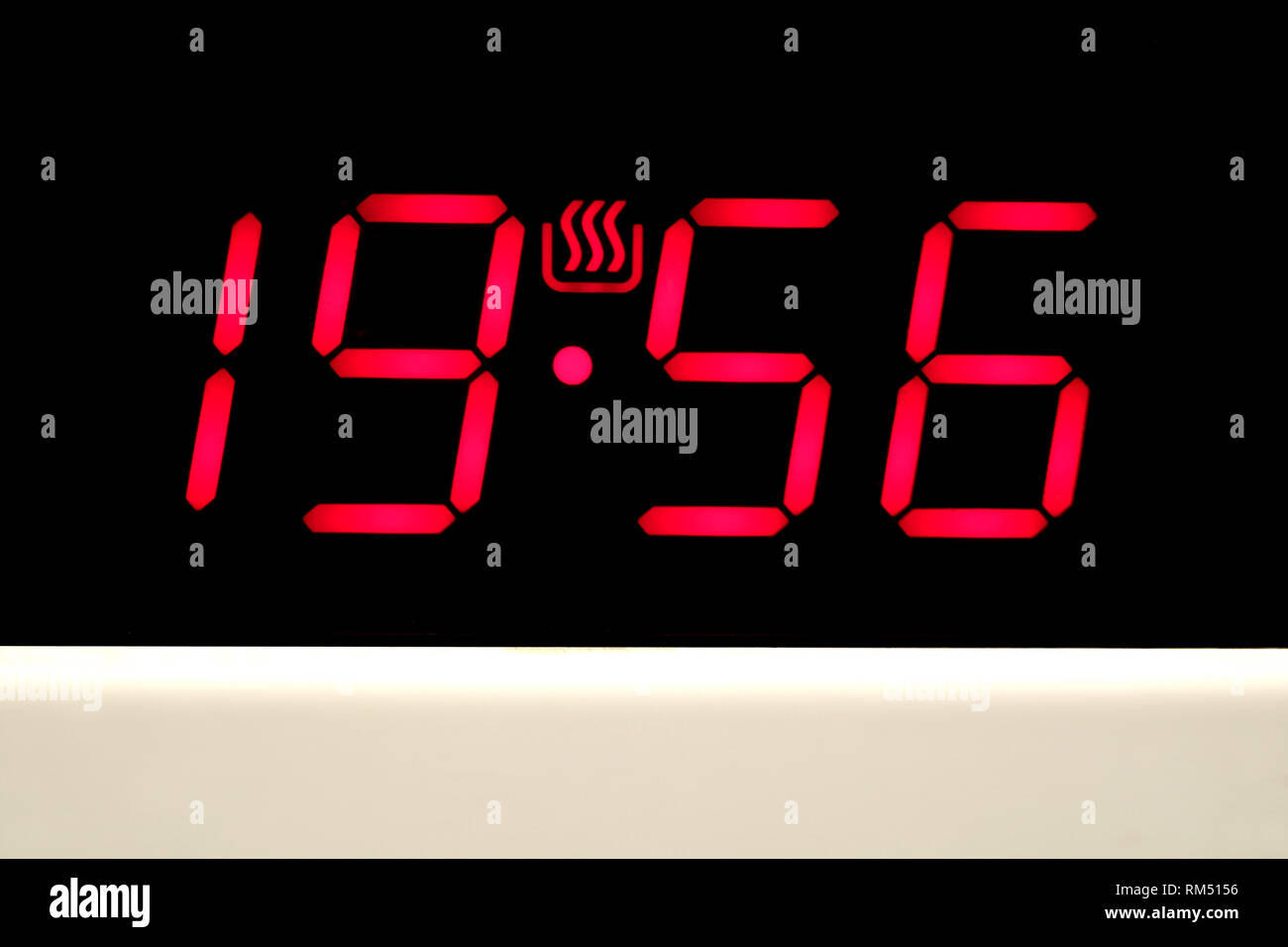 Control panel with red digits on electronic timer display on modern white kitchen electric stove front view closeup Stock Photo