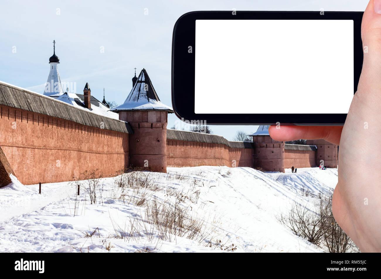 travel concept - tourist photographs of walls of Monastery of Our Savior and St Euthymius in Suzdal town in winter of Russia on smartphone with cutout Stock Photo