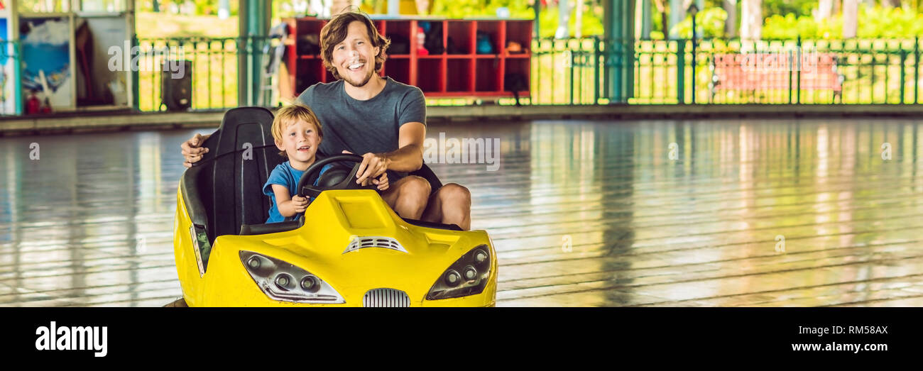 Father and son having a ride in the bumper car at the amusement park ...