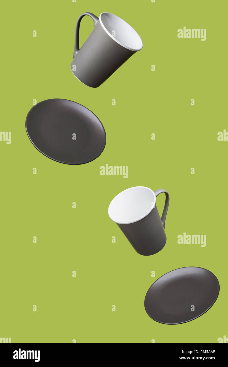 Flying Concept of Gray Brown Porcelain Coffee Tea Cups and Plates on Green Background Decorative Minimal Style Background Stock Photo