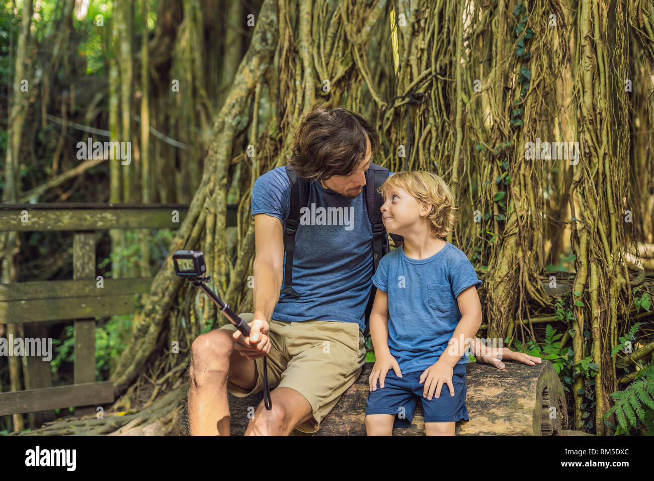 Dad and son travelers discovering Ubud forest in Monkey forest, Bali Indonesia. Traveling with children concept. Videoblog, Selfie. Stock Photo