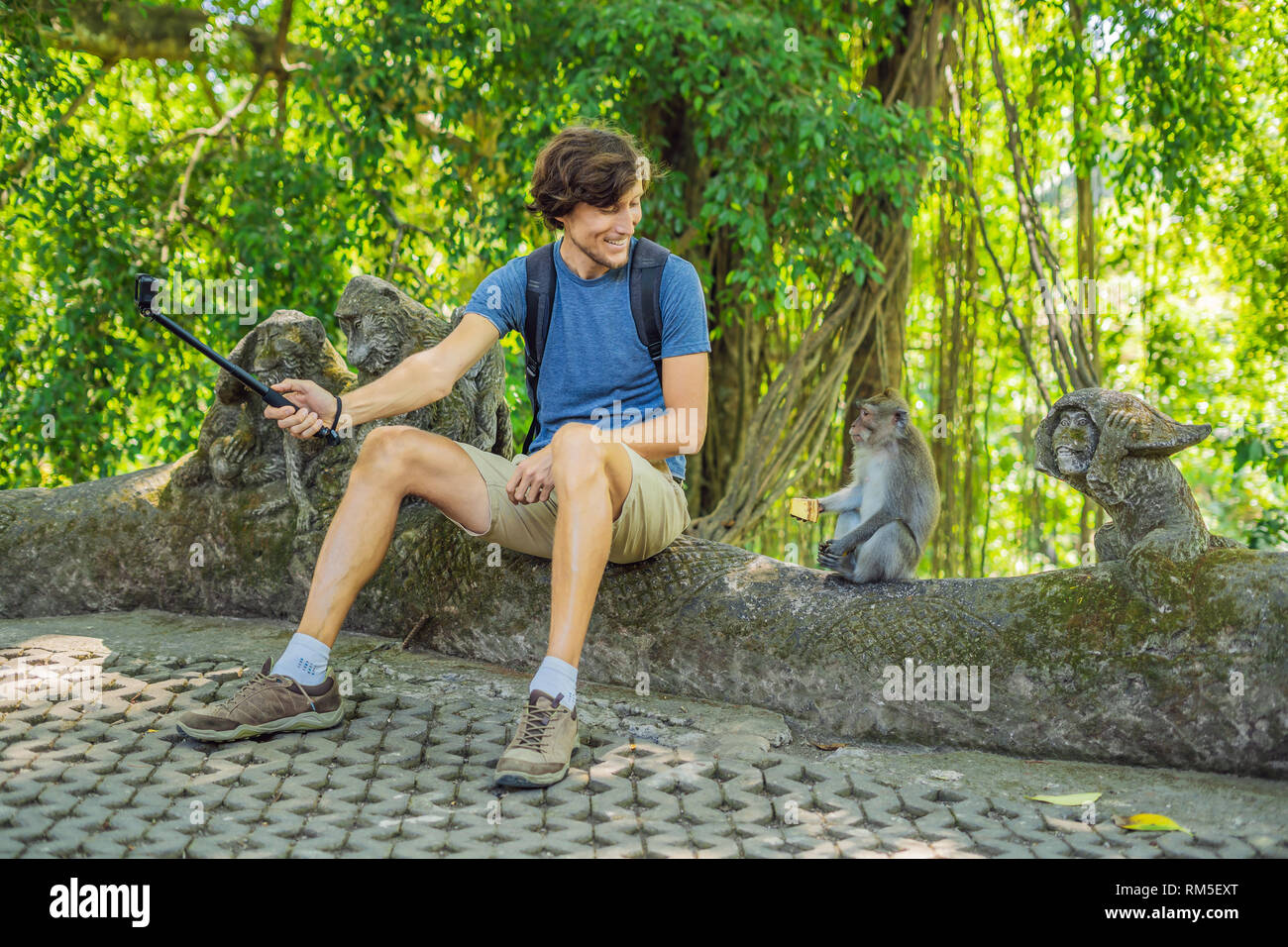 Selfie with monkeys. Young man uses a selfie stick to take a photo or video  blog with cute funny monkey. Travel selfie with wildlife in Bali Stock  Photo - Alamy