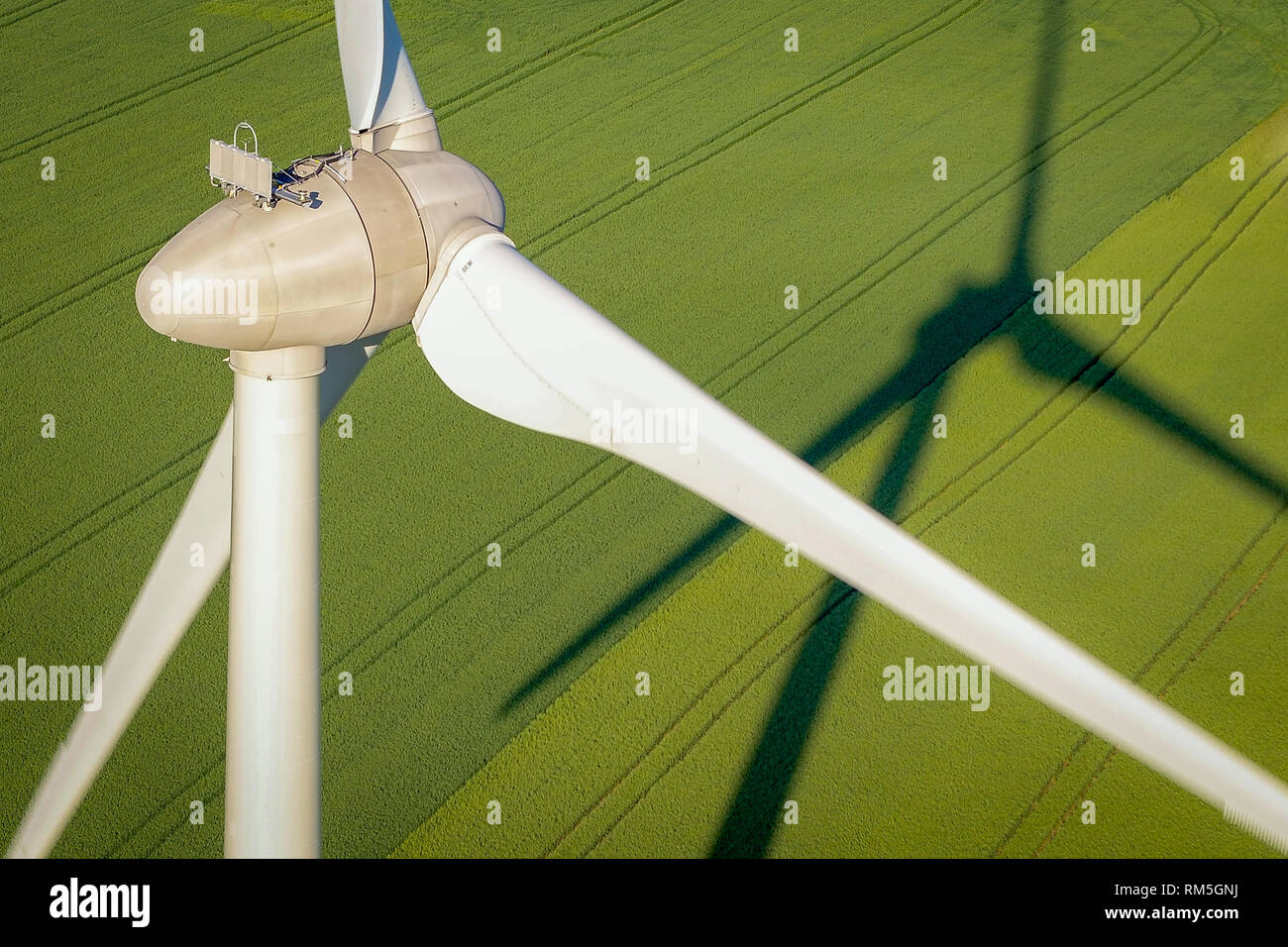 Overhead aerial view of a wind farm turbine and its shadow reflected on