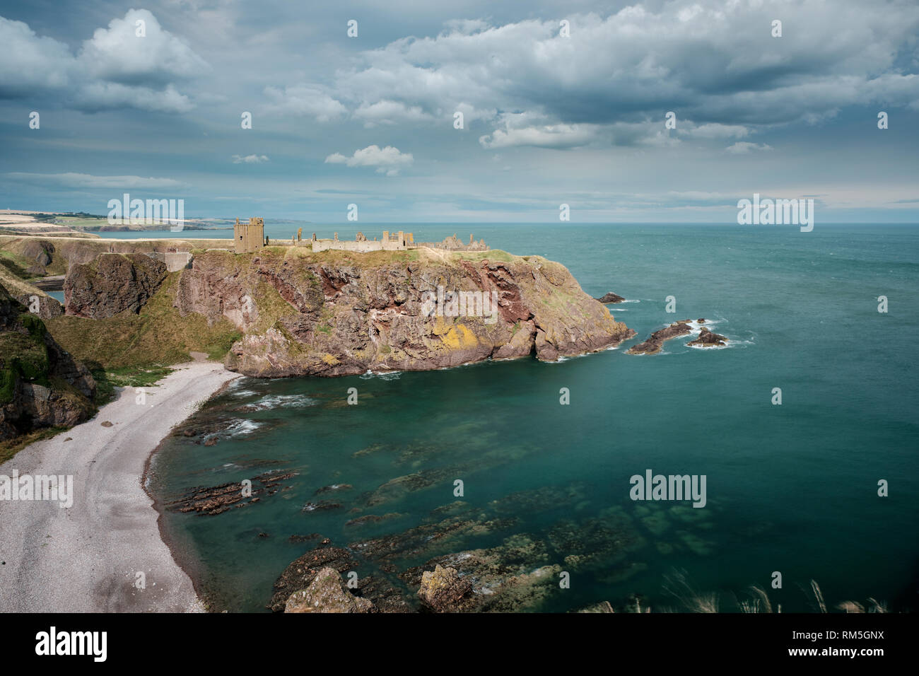 Dunnottar castle ruin and the surrounding coastline, bathed in sunshine with clouds overhead, Stonehaven, Aberdeenshire, Scotland Stock Photo