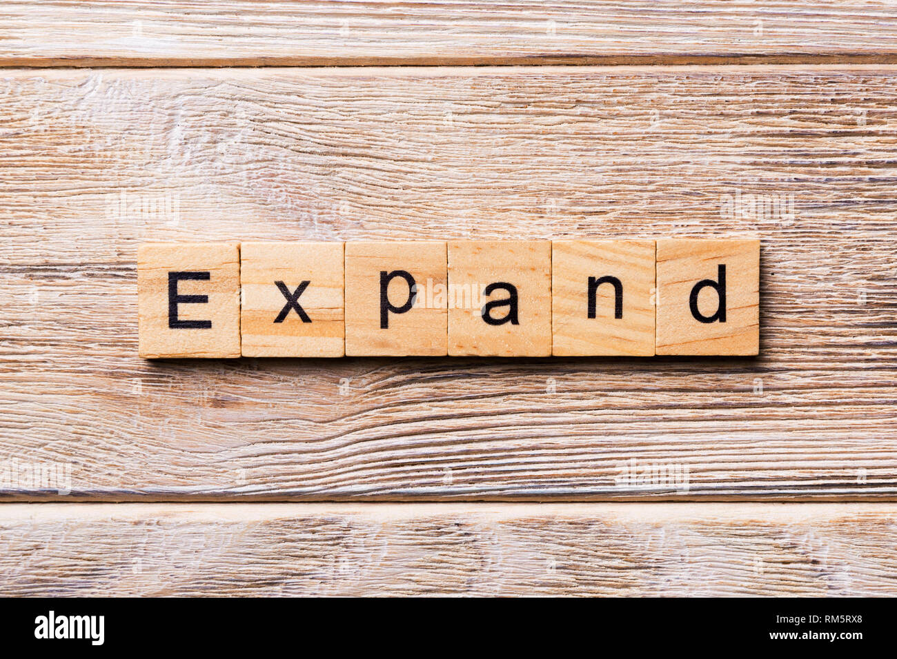EXPAND word written on wood block. EXPAND text on wooden table for your desing, concept Stock