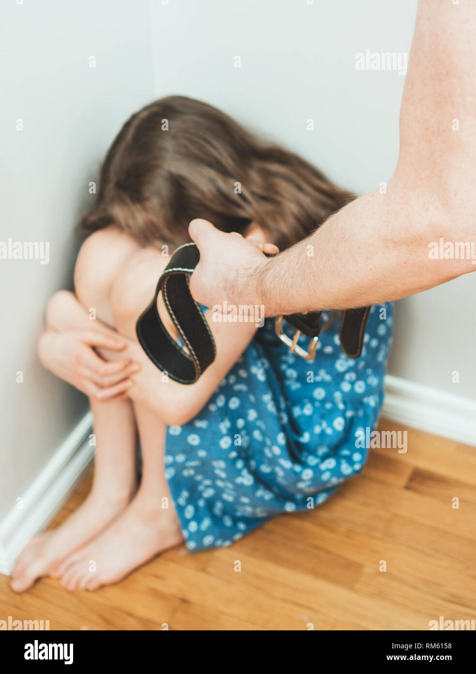 Little girl crying in the corner. Domestic violence concept. Stock Photo